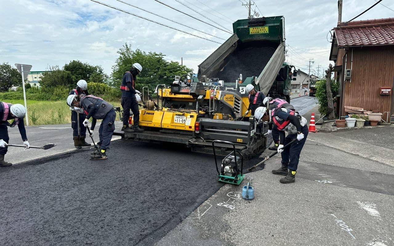 道路を舗装する作業員と重機の様子の写真